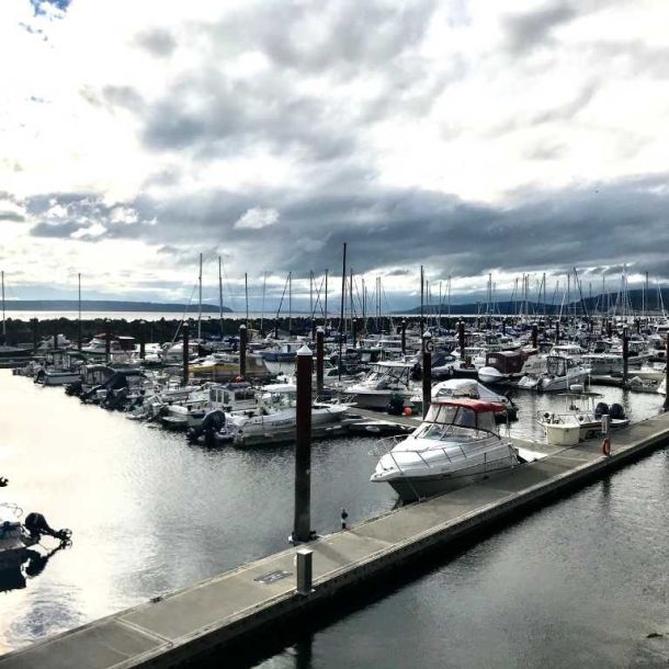 Photo of marina dock and boats along the water with grey clouds in the sky