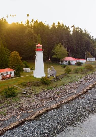 Landscape photo of Quadra Island lighthouse with forest and sunrise in the background