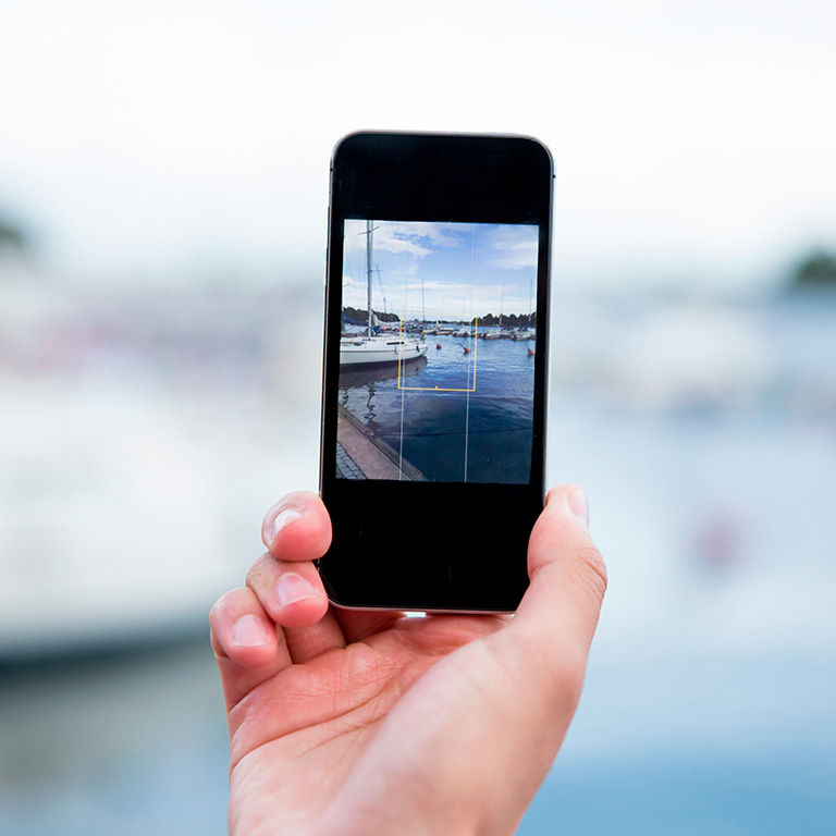 Hand holding cell phone at the marina