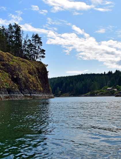 Quadra Island green ocean, water and forest and blue clouds in the background